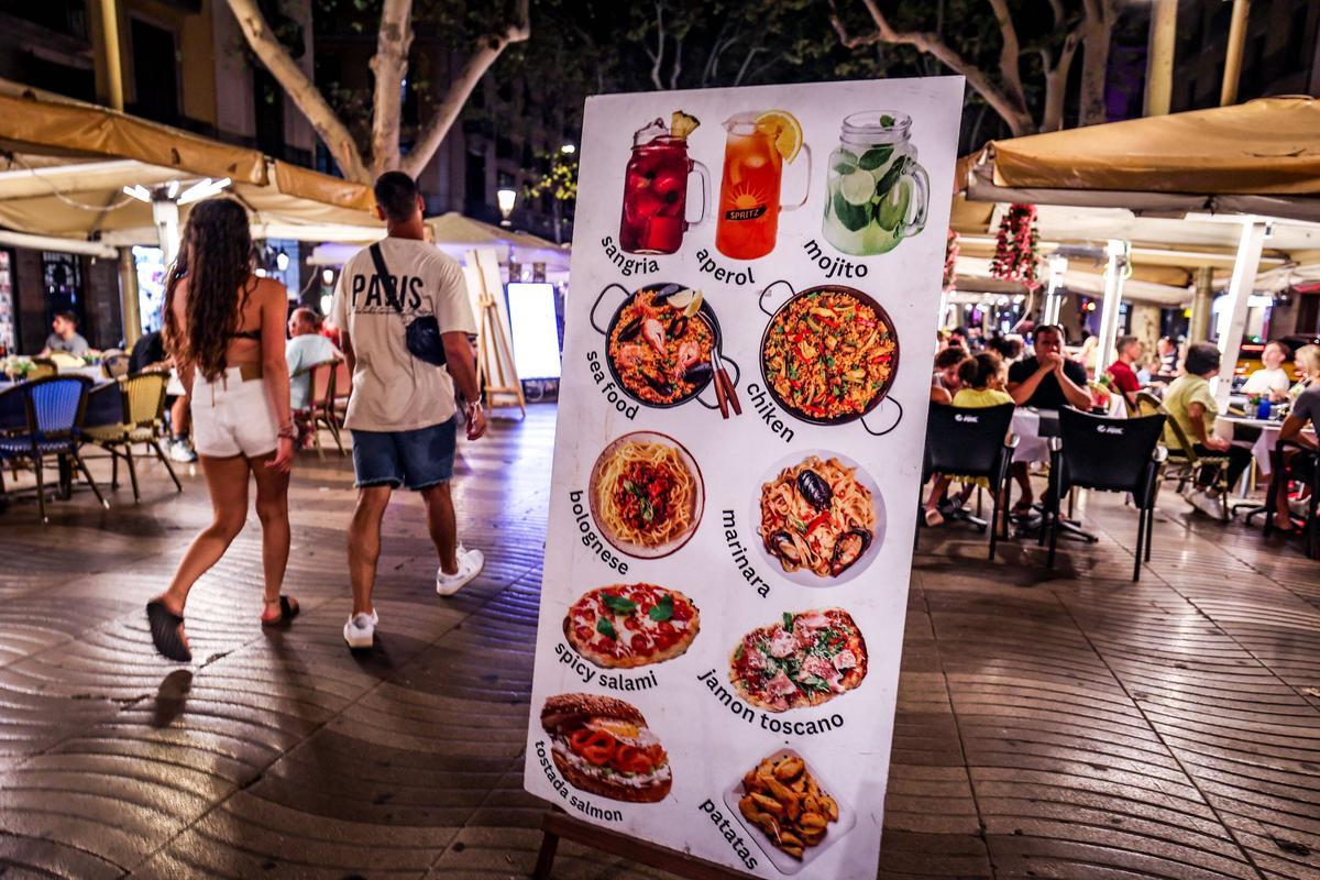 Un cartel anuncia bebidas alcohólicas y comida junto a las terrazas de la Rambla.