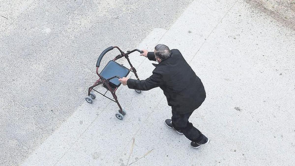 Una persona mayor camina con ayuda de un andador, sola, en las calles de Zaragoza