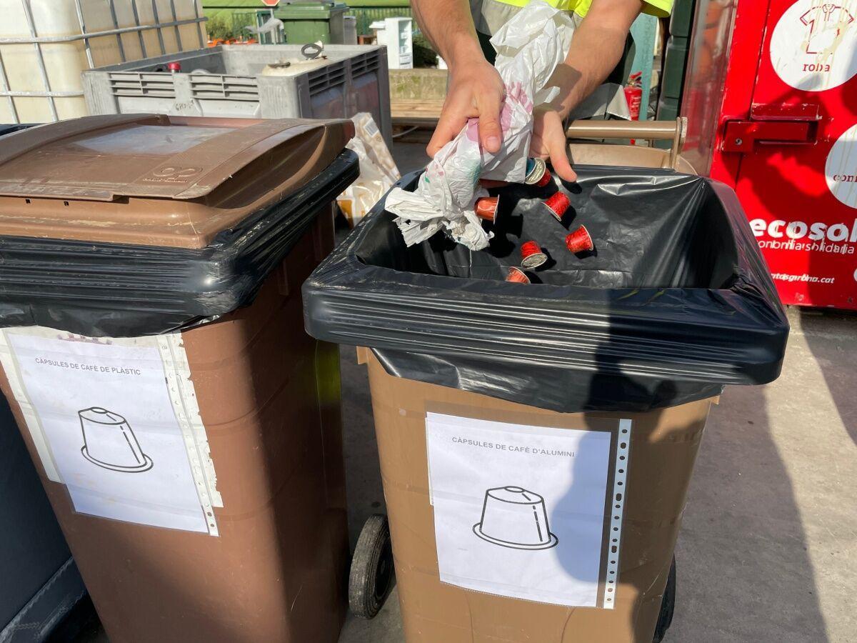 Una persona reciclando: tira las cápsulas de café en un contenedor especial para ello (L'Escala).