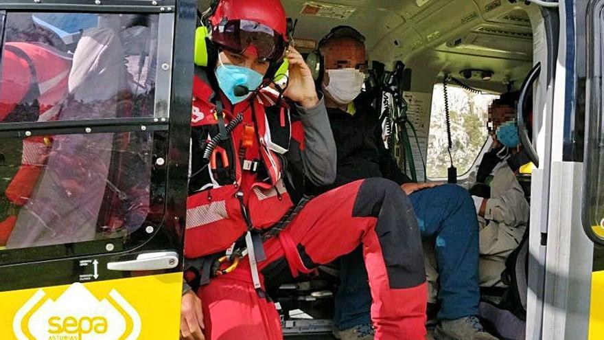 Los dos montañeros indispuestos, a bordo del helicóptero, junto a un miembro de los equipos de rescate.
