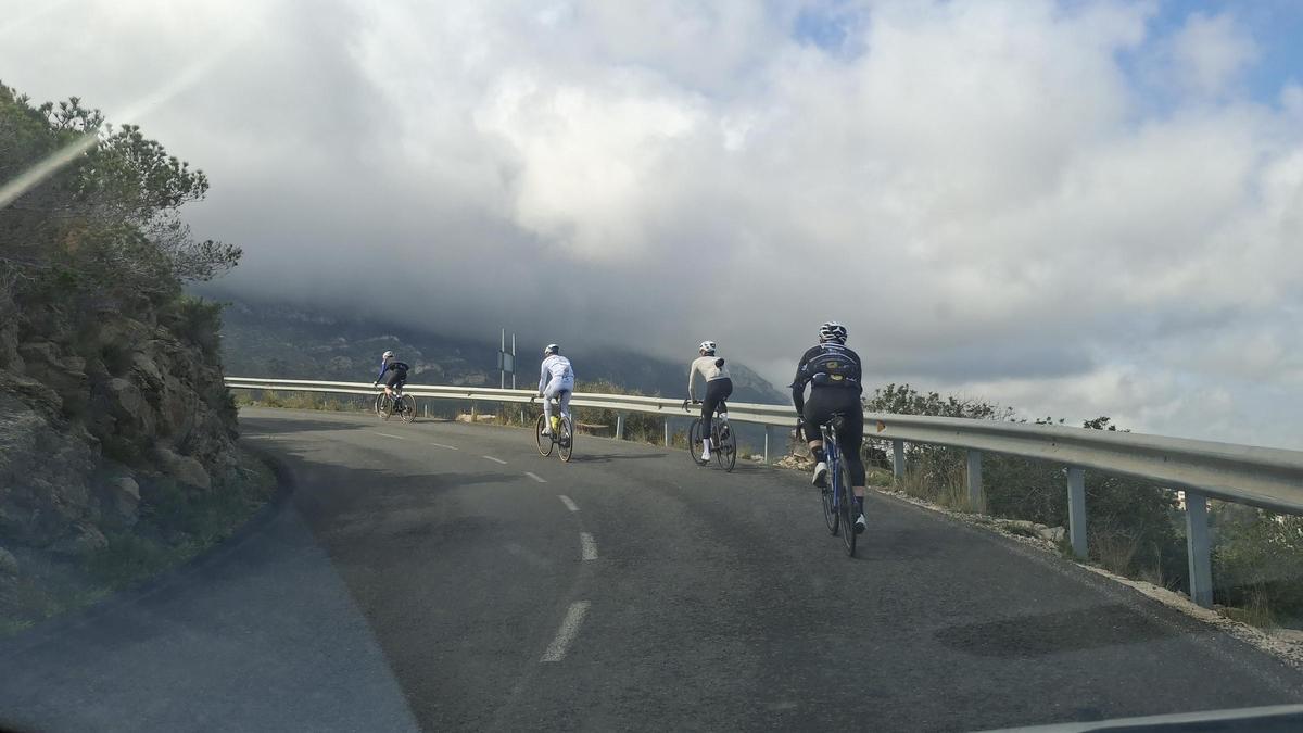 Ciclistas ascienden por la vertiente de Dénia de la carretera de les Planes