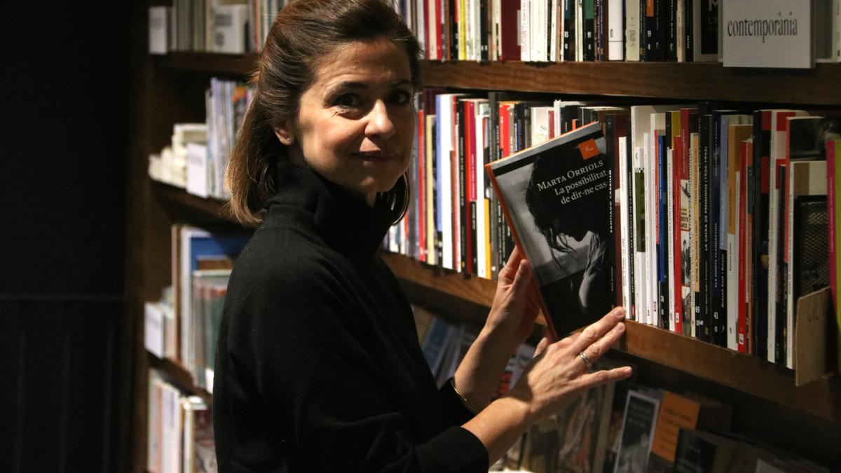 Marta Orriols, fotografiada a la llibreria Ona, agafant un exemplar del seu darrer llibre