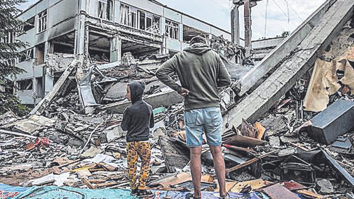 Un hombre y su hijo contemplan los escombros de un colegio atacado por las fuerzas rusas en Járkov.