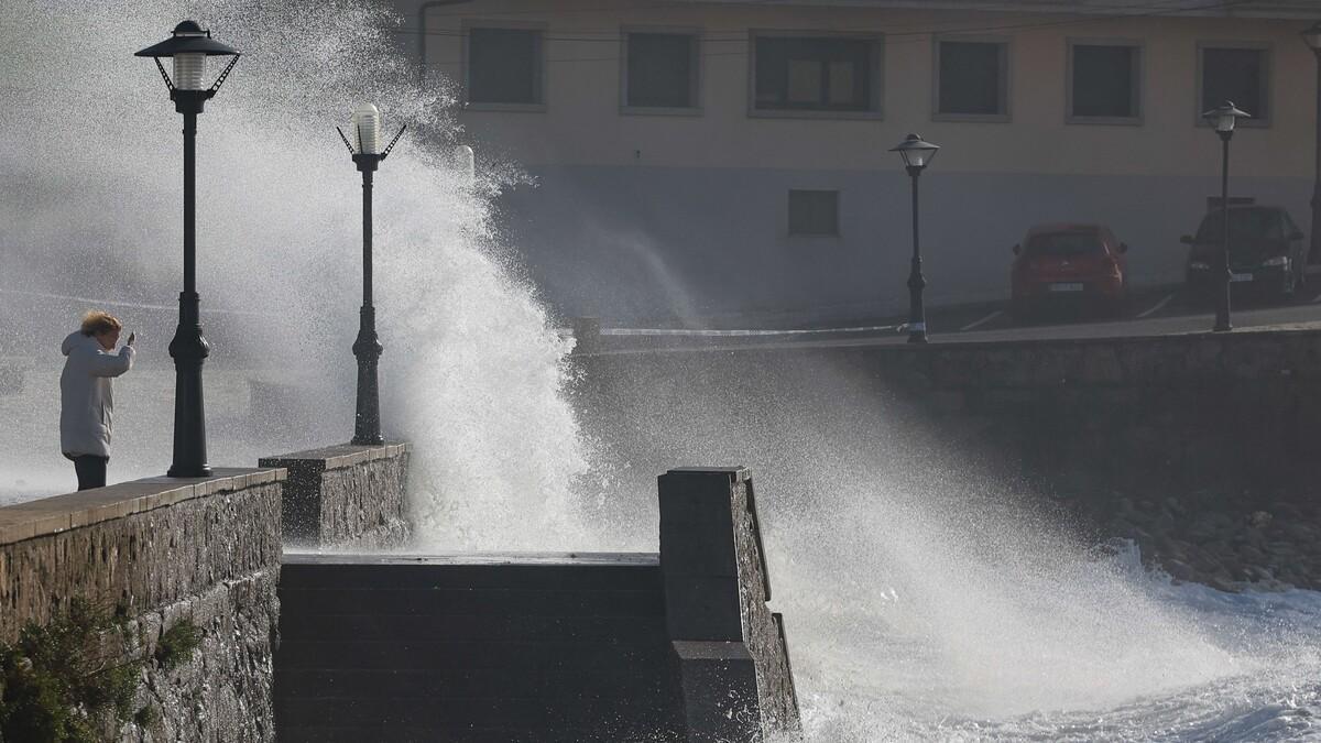 Una mujer se protege del oleaje durante un día de temporal en Galicia