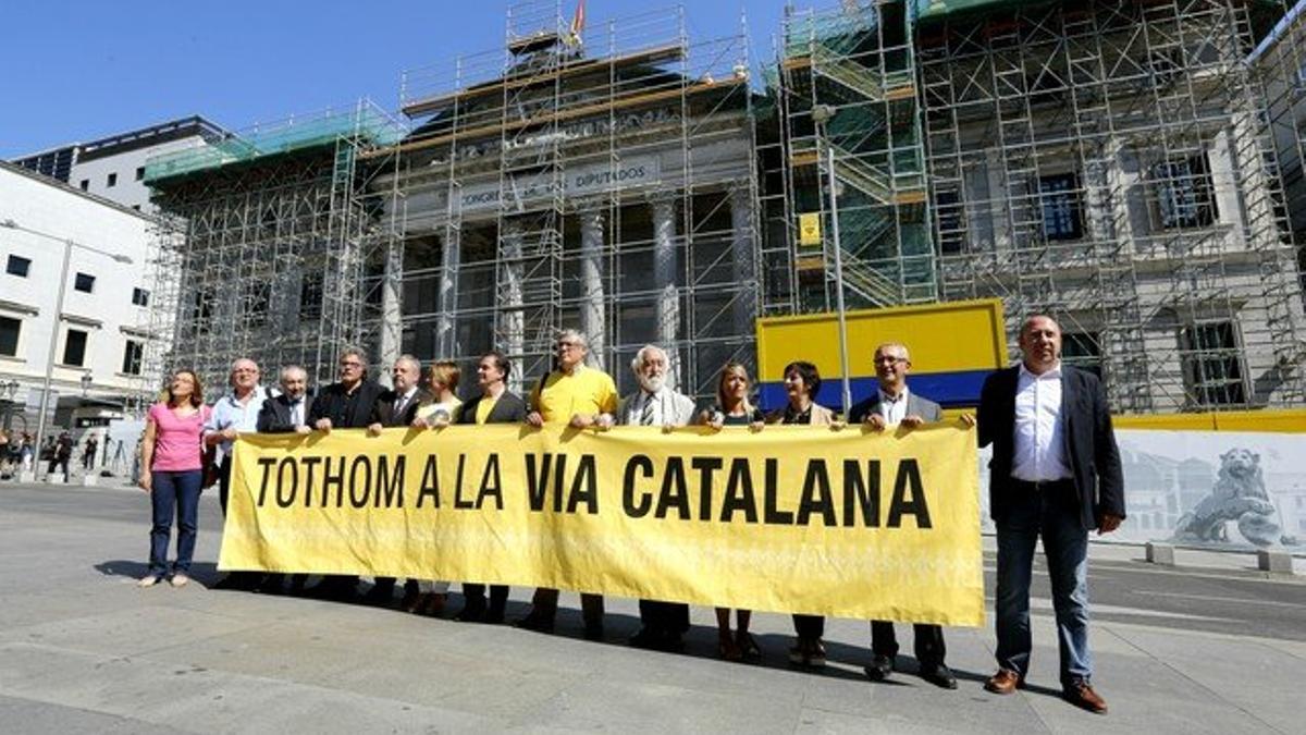 Diputados y senadores catalanes, con una pancarta en apoyo de la Via Catalana, este jueves ante el Congreso.