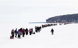 Desenes de turistes travessen a peu el llac en direcció a les coves de gel, a les illes Apostle.