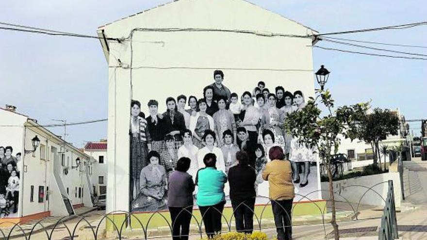 Mujeres del pueblo contemplando la fotografía en la fachada.