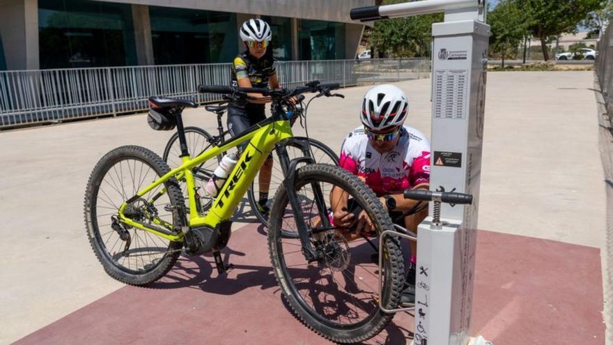 Dos usuarios supervisan sus bicis junto al Palacio de los Deportes. | A. C.