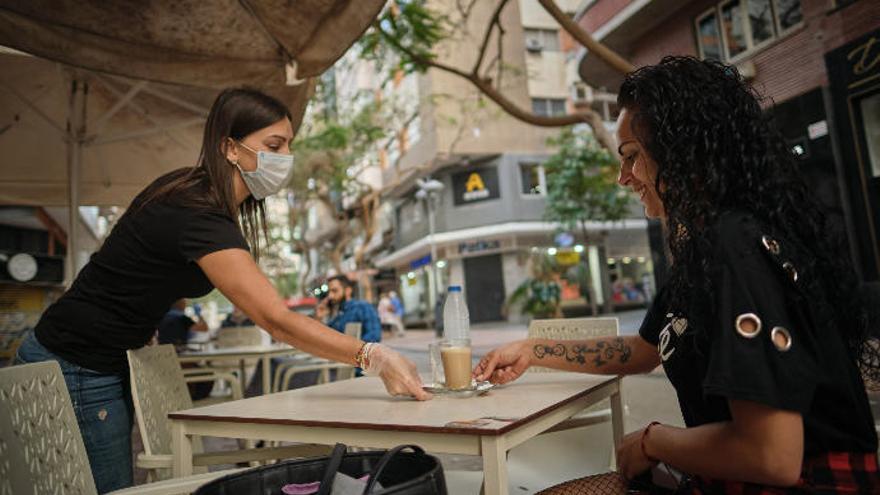 Una camarera atienda a una clienta en la terraza.