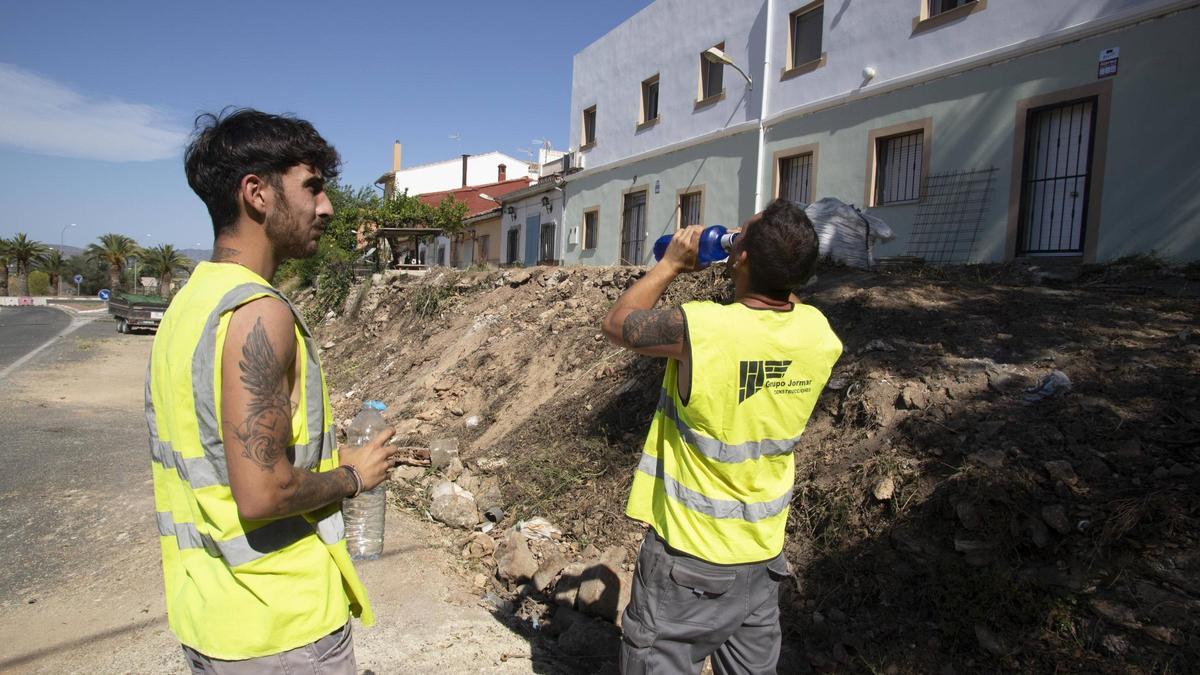 Dos trabajadores se hidratan en medio de una intensa jornada de calor en Xàtiva.