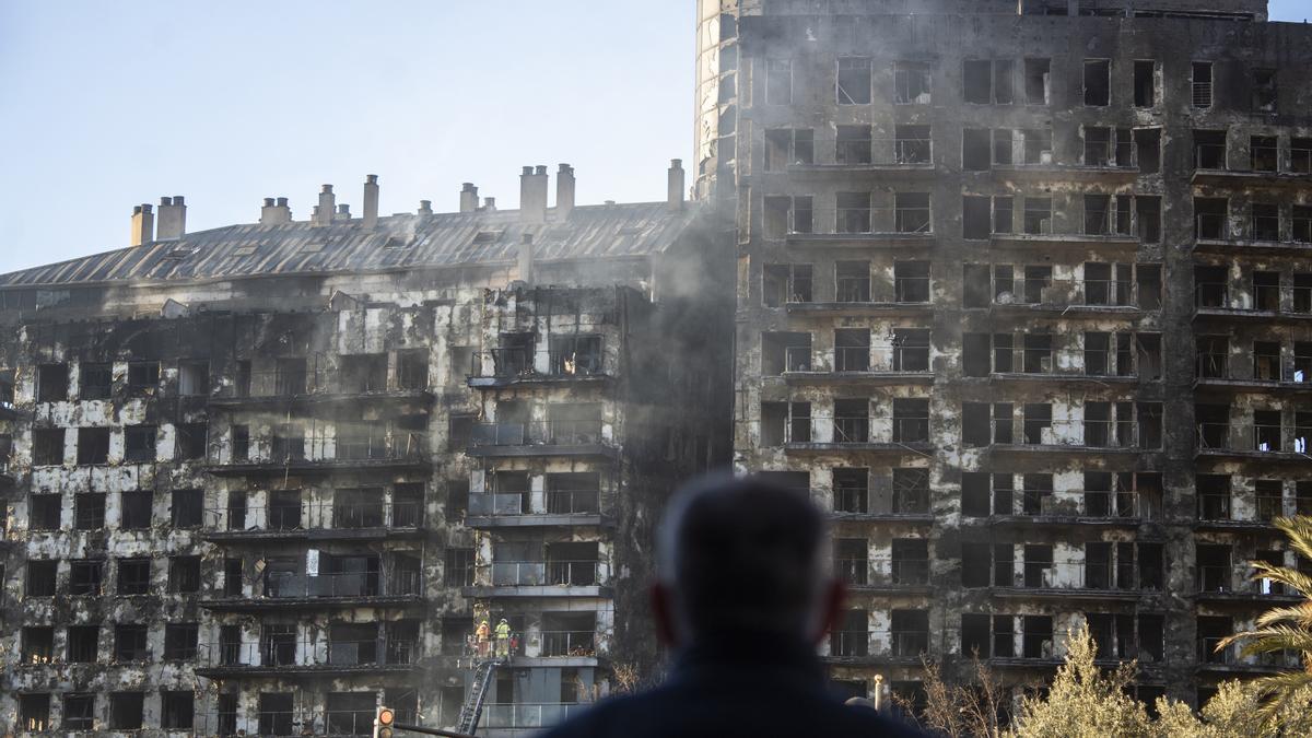 Un hombre observa la estructura del edificio de Valencia tras el incendio.