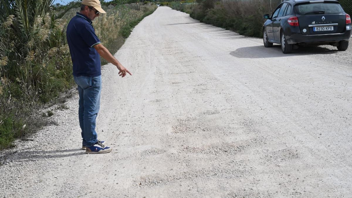 Un vecino señala los baches mientras pasan coches alrededor