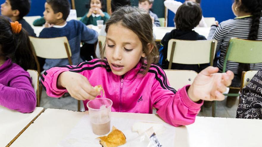 Una niña desayuna un vaso de leche en un comedor.