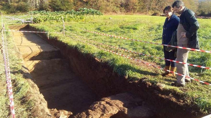 Magariños y otra integrante del Consello Local del BNG, junto a la estructura pétrea hallada en un foso.