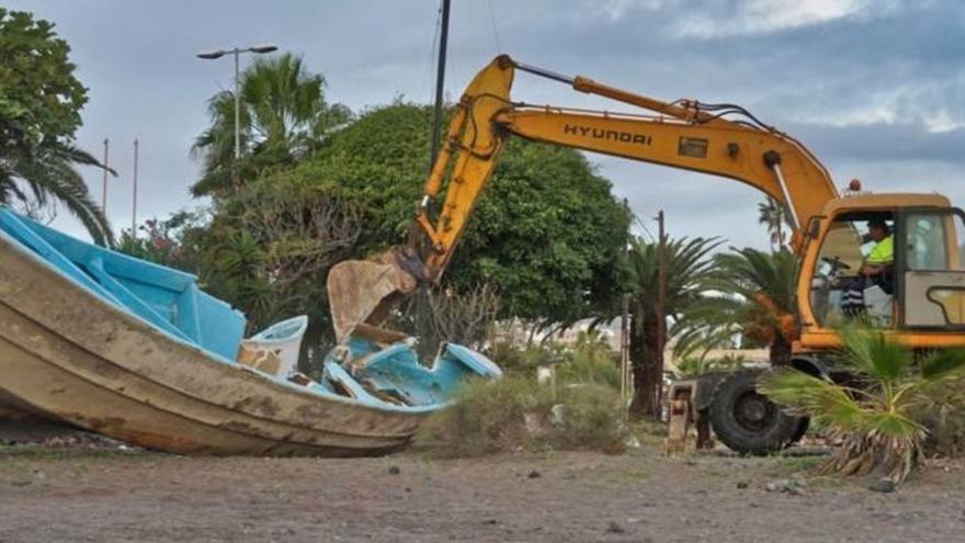 Una excavadora destruye este lunes uno de los dos cayucos que permanecieron durante meses en la playa de Las Galletas, en el municipio de Arona.