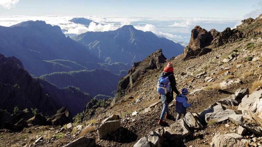 Un adulto y un niño pasean por un sendero de las cumbres de La Palma.