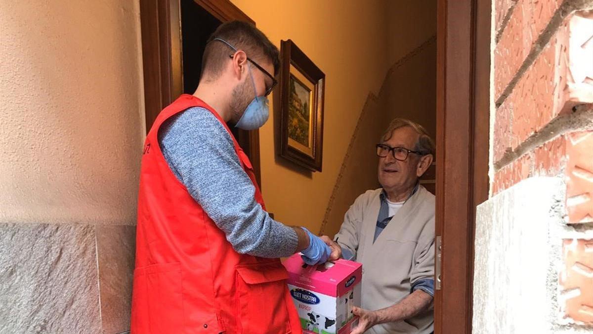 Un miembro de la Cruz Roja entrega leche a un ciudadano mayor.