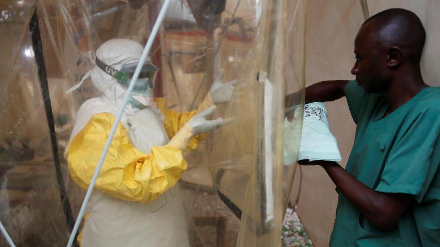 Un hombre se protege antes de tratar a enfermos de ébola.