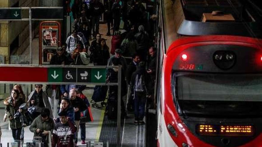 Un tren y numerosos viajeros en la estación de Oviedo.