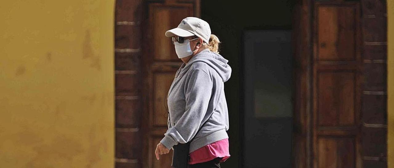 Una mujer pasea con mascarilla por La Laguna.