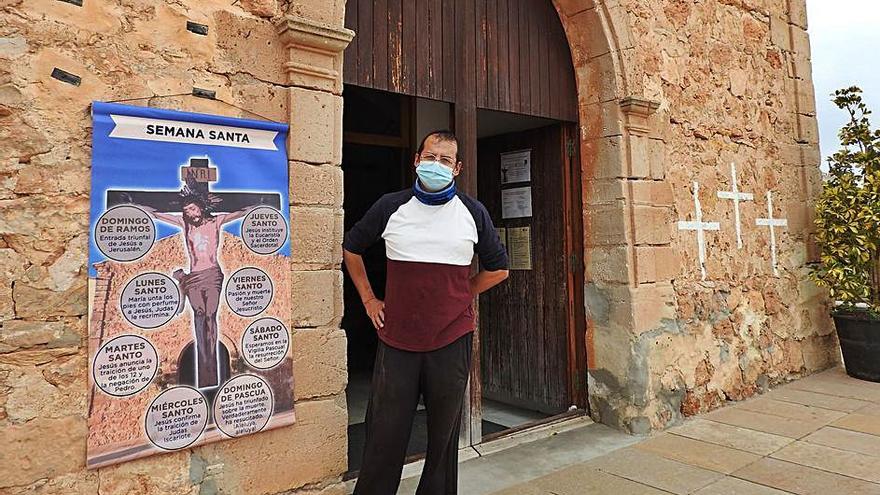 El párroco, Vicente Baudilio Piedra Carrión, ante un cartel colocado en la fachada de la iglesia que explica la Semana Santa.