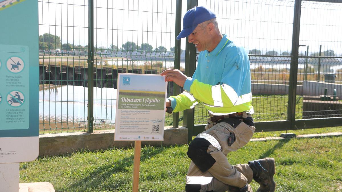 Un operari col·locant un cartell informatiu del procés de participació al parc de l&#039;Agulla