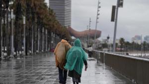 Vecinos de Barcelona pasean bajo la lluvia en la playa de la Barceloneta. Archivo