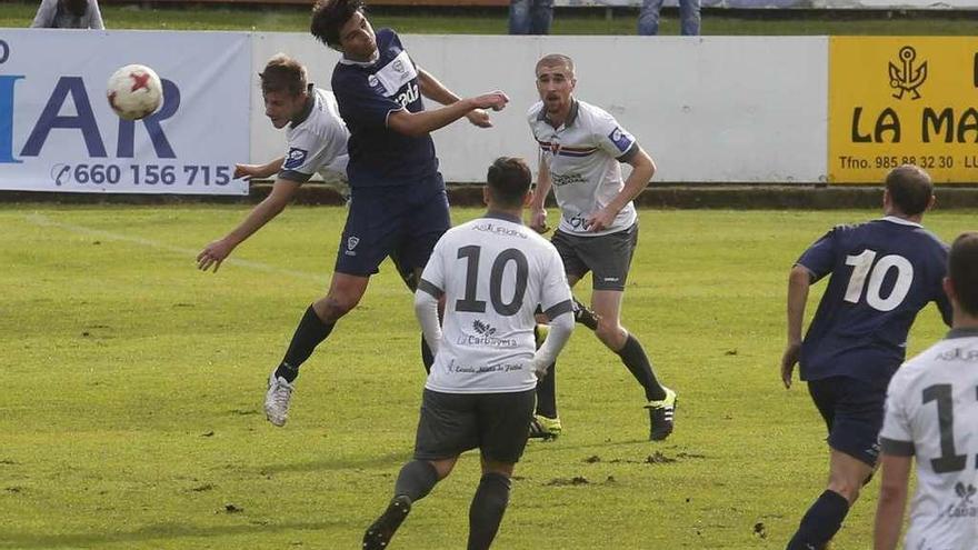 Jairo Cárcaba cabecea el balón, rodeado de contrarios, con Luis Morán de espaldas.