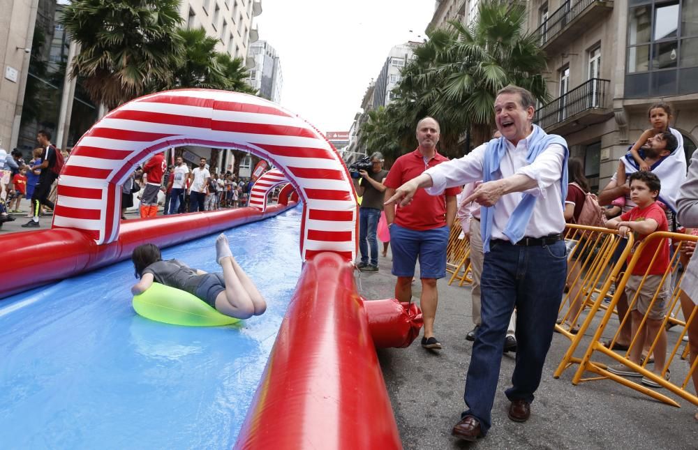 Cientos de personas disfrutan del tobogán acuático en la calle Colón