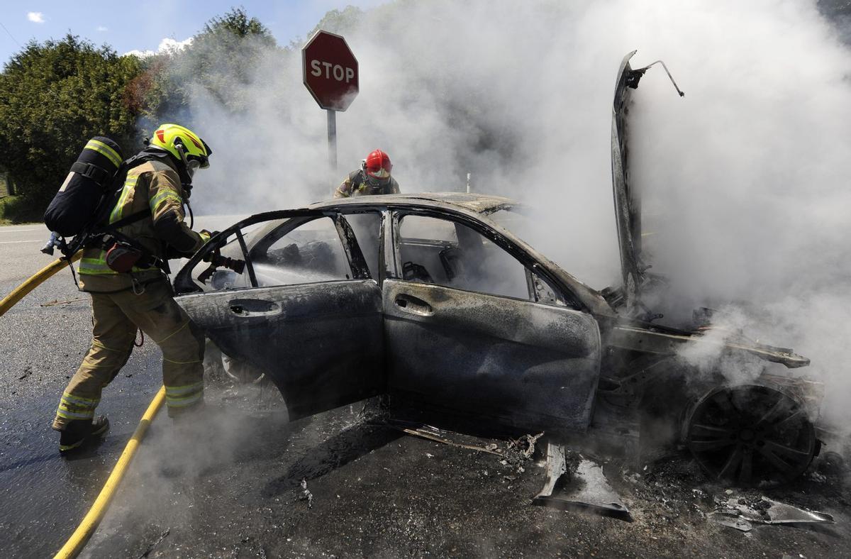 Dos bomberos sofocan el incendio en un vehículo en la N-525, en Lamela. | BERNABÉ/JAVIER LALÍN