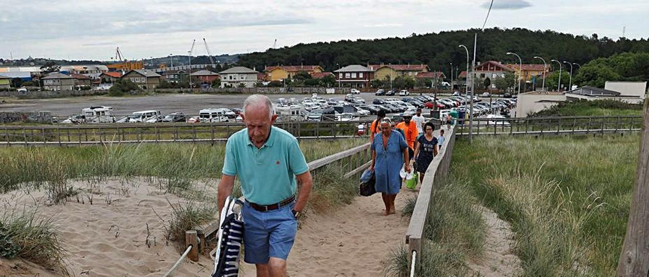 Ciudadanos accediendo a la playa de San Juan con las pasarelas invadidas por la arena, el verano pasado.