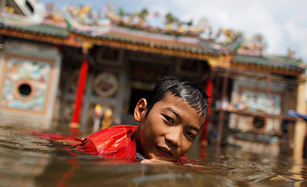 Un noi juga a l’aigua davant un temple inundat a la zona de Chinatown, al centre de Bangkok.