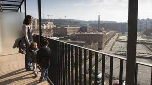 Los pequeños Otger y Guifré miran los terrenos de Can Batlló desde el balcón de su nueva casa, junto a Ares, su madre, este sábado.