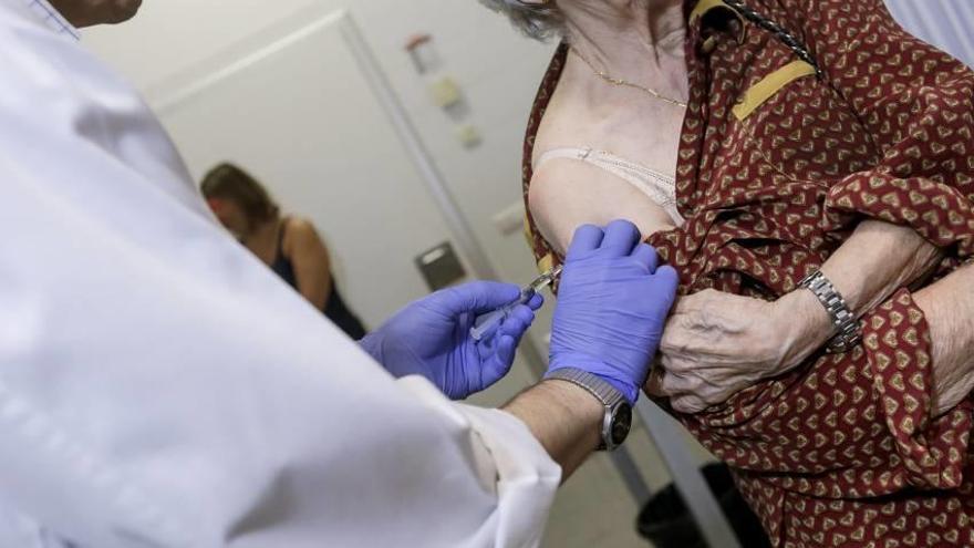 Un profesional sanitario administra la vacuna antigripal a una paciente el curso pasado.