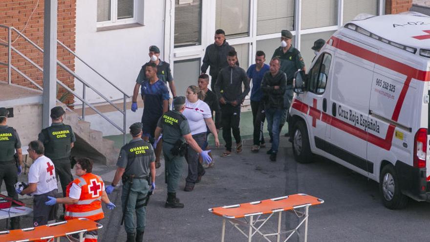 Guardias civiles y voluntarios de Cruz Roja con inmigrantes llegados el domingo a Alicante.