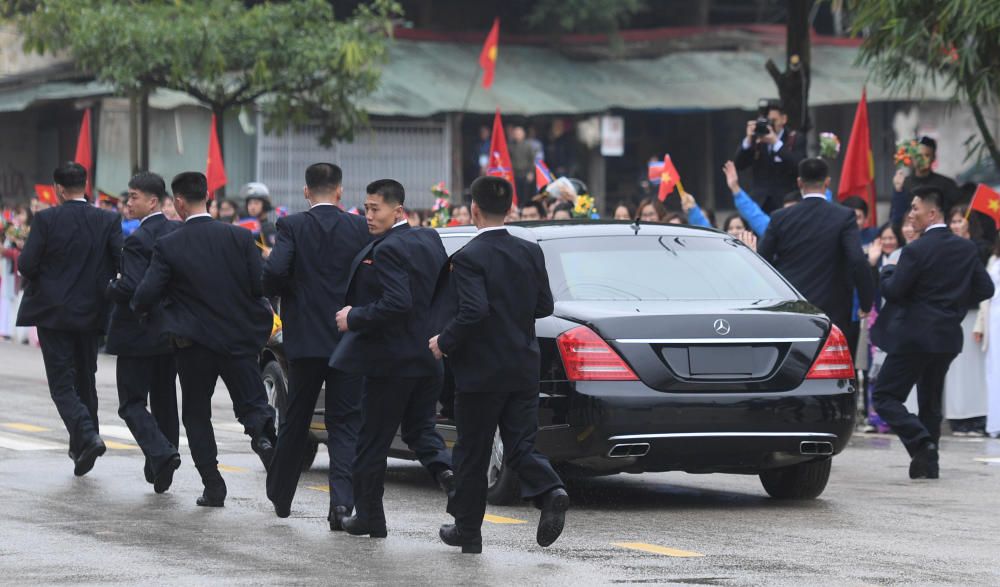 North Korean bodyguards run along a limousine ...