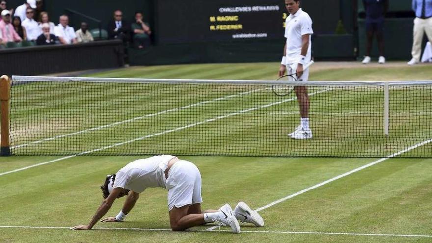 Raonic observa a Federer tras su aparatosa caída en el quinto set. // Efe