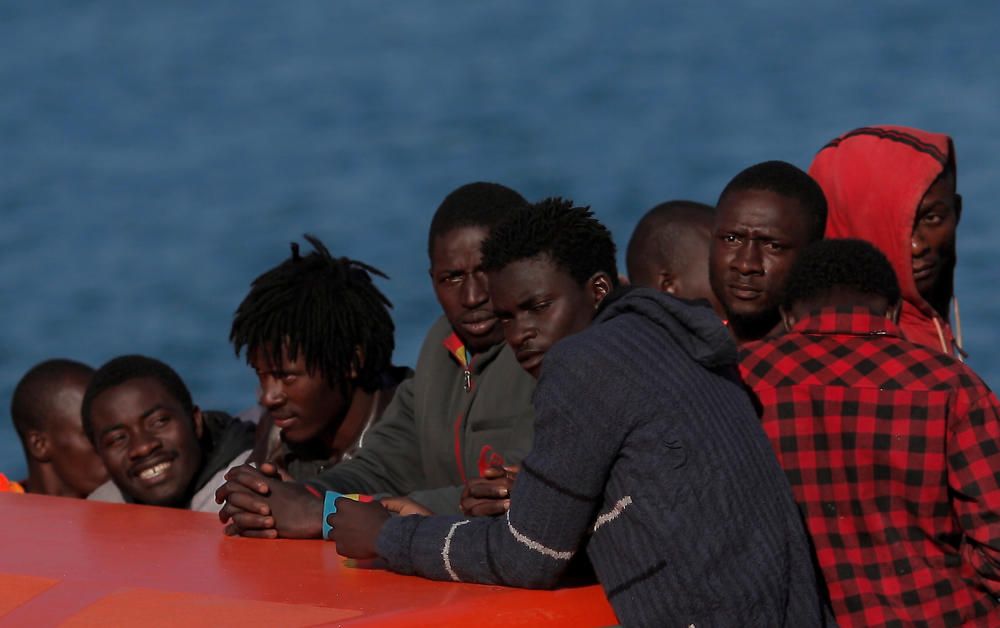 Migrants stand on a rescue boat upon arriving at ...