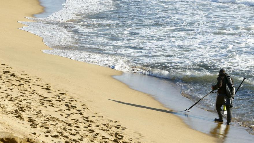 Un home utilitza un detector de metalls en una platja de Barcelona després d’una tempesta el 28 de desembre. | QUIQUE GARCÍA / EFE