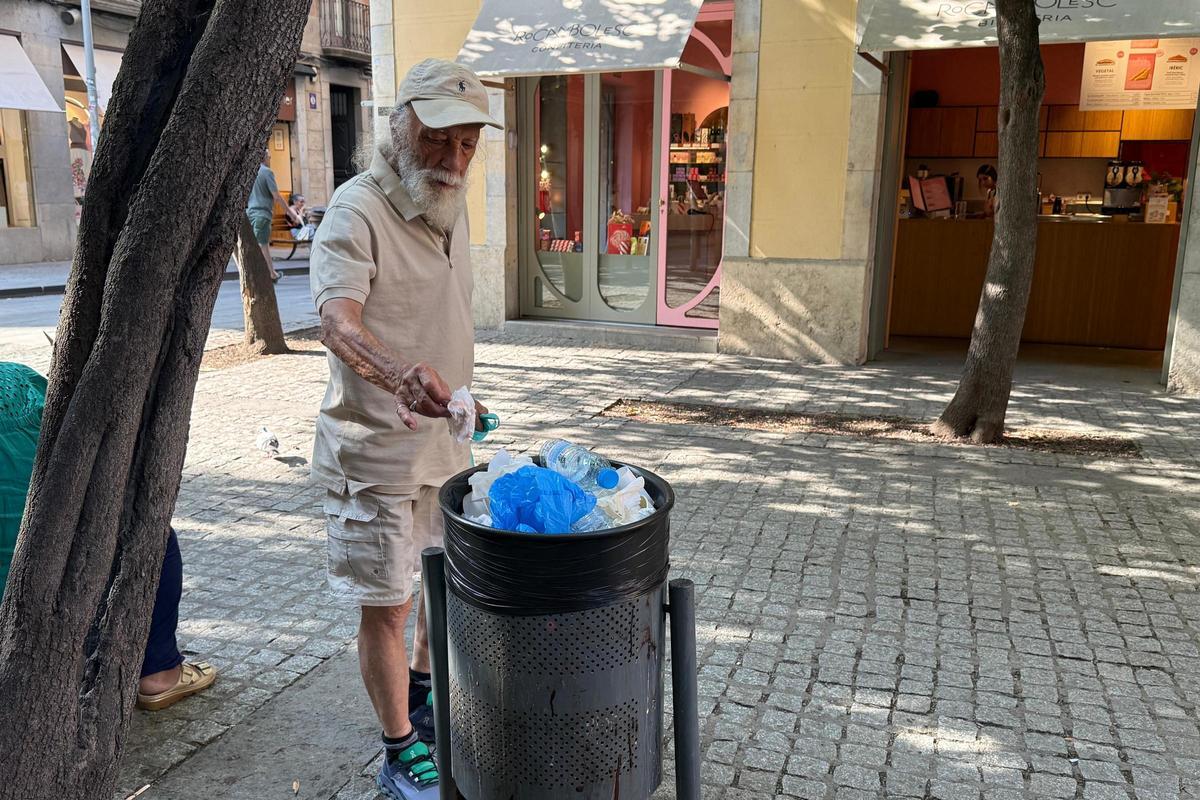 Un home tira un embolcall a una paperera a Girona.