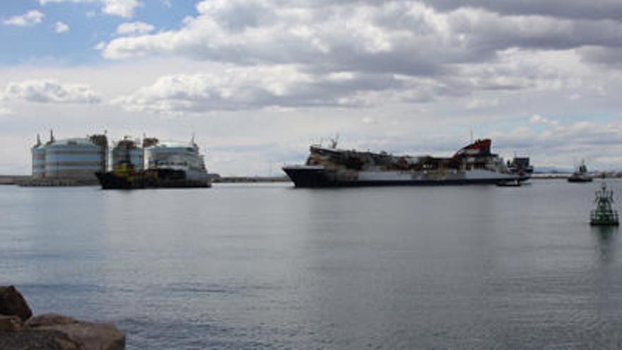 El Sorrento, al dejar Sagunt remolcado por el «Agat» y con la regasificadora al fondo.