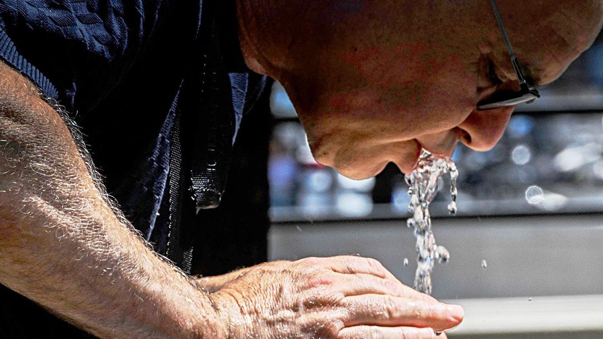 Un hombre bebe agua para mitigar el calor.