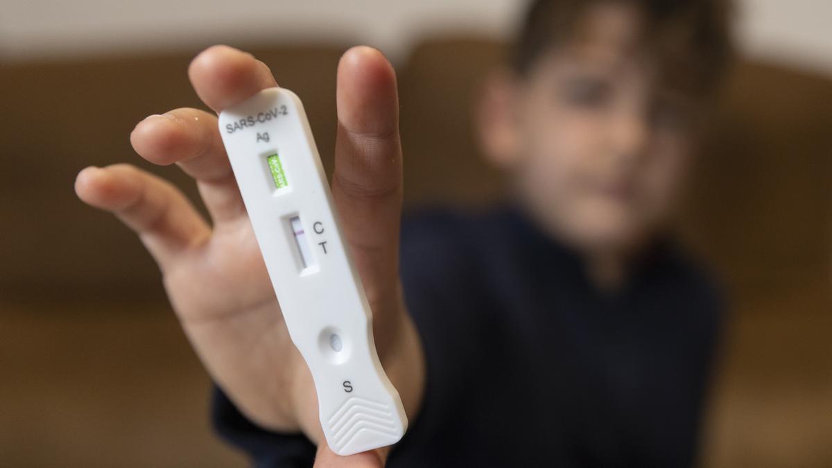 Un niño enseña un test de antígenos