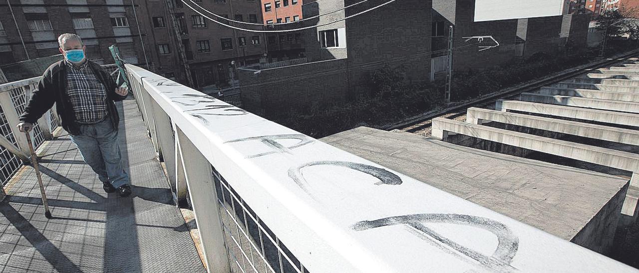 Un hombre atraviesa la pasarela que salva las vías en la calle La Unión.