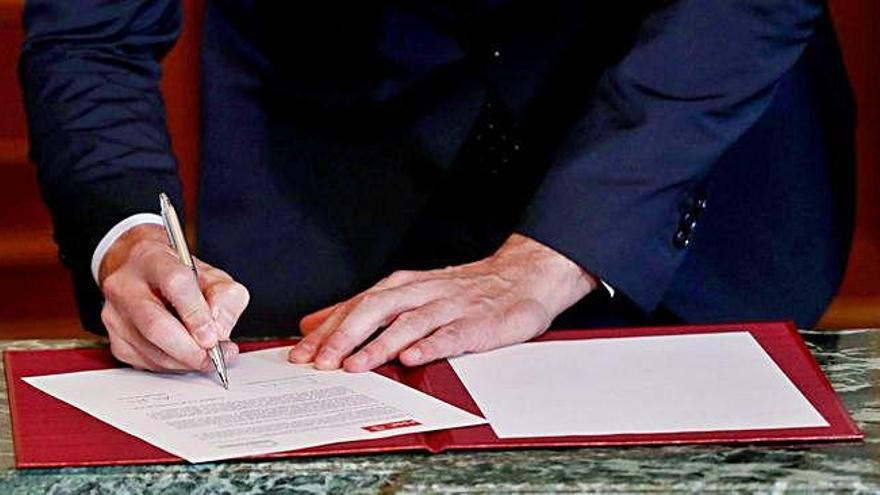 Detalle de las manos de Pedro Sánchez (izquierda) y Pablo Iglesias al firmar, ayer, el documento de preacuerdo para un gobierno de coalición de PSOE y Unidas Podemos.