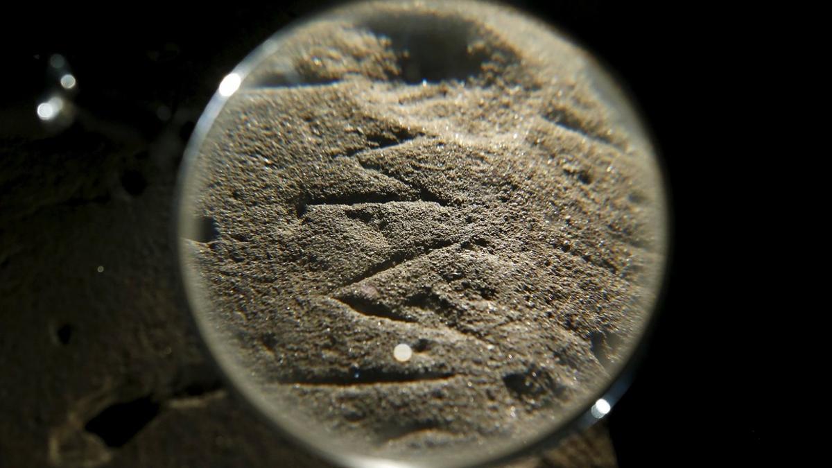 An inscription on an Etruscan stele is seen through a magnifying glass in a restoration centre in Florence