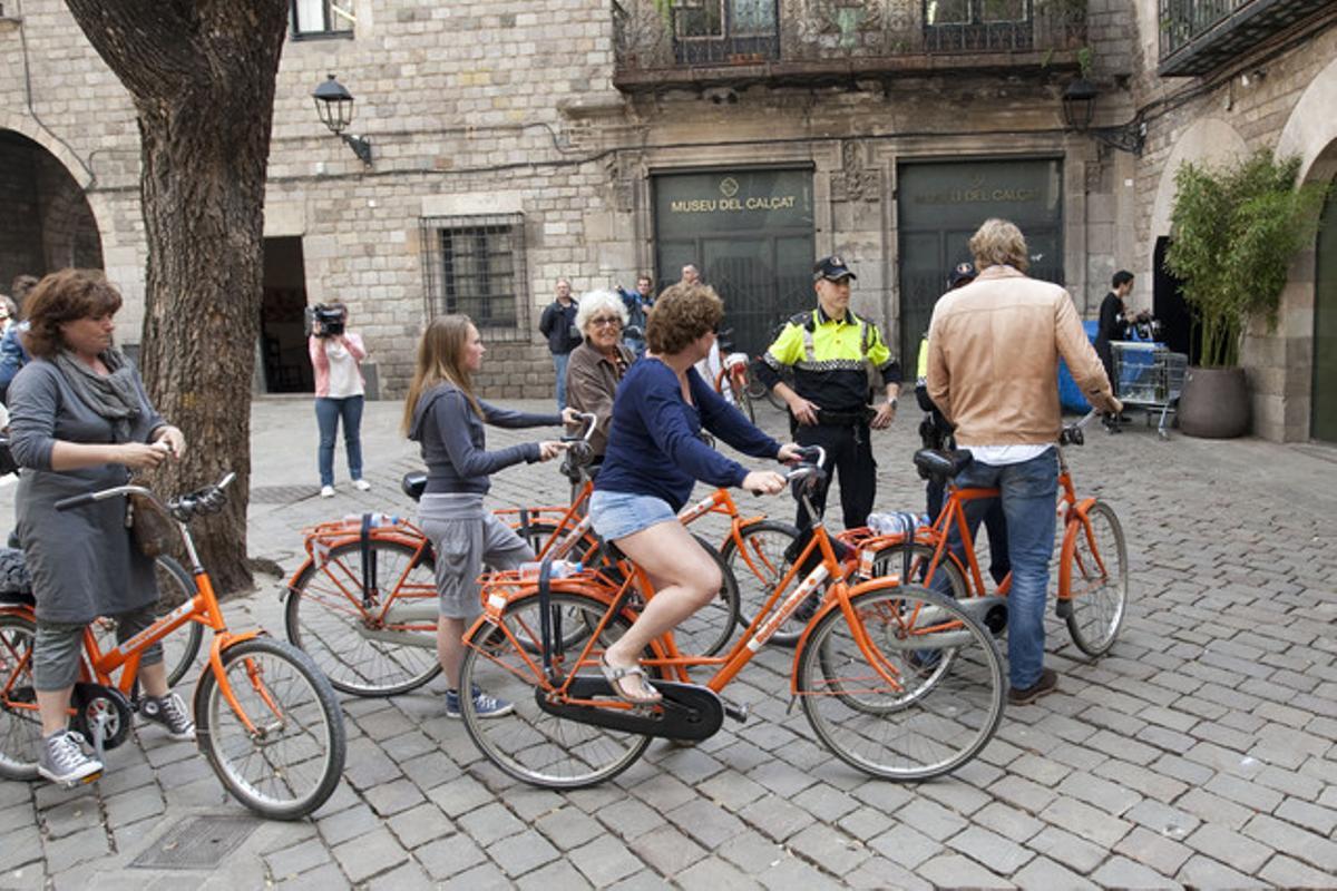 Un guardia urbano informa de la ordenanza a turistas en bicicleta.
