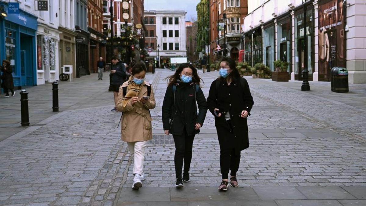 Personas con máscaras caminan en una tarde inusualmente tranquila en Covent Garden, en Londres.