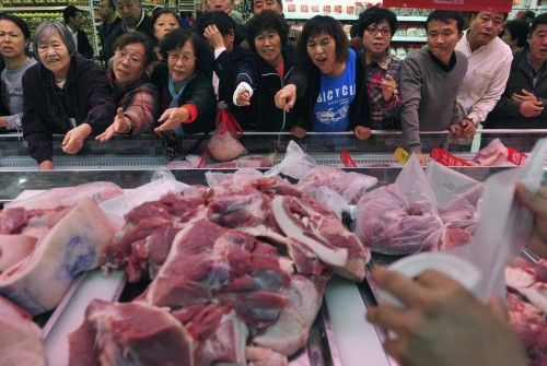 Los clientes se agolpan frente a un mostrador con carne de cerdo picada a la venta durante un acto promocional