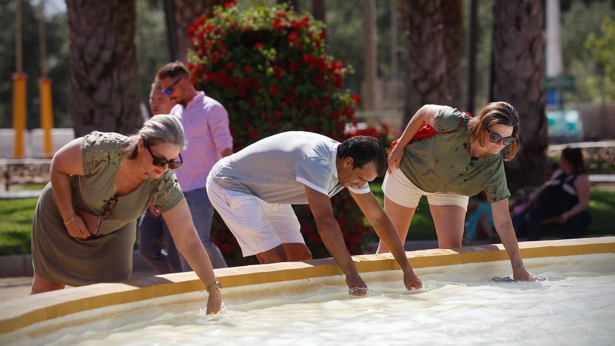 Tres personas se refrescan en la Feria de Córdoba.
